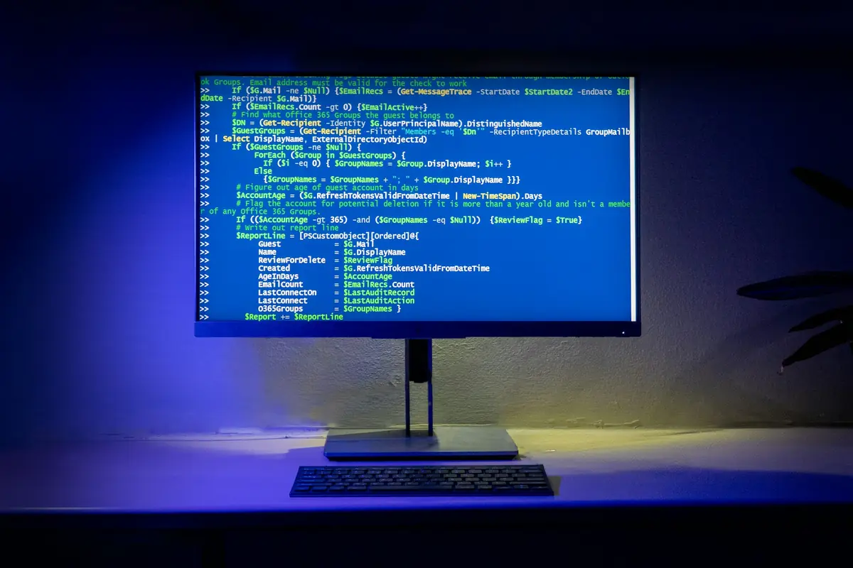 Monitor showing source code in a blue-lit workspace